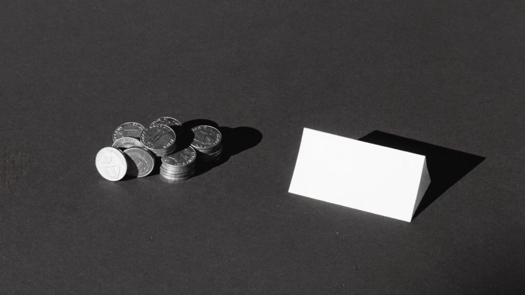 机の上に置かれた硬貨と白いカード（白黒写真）