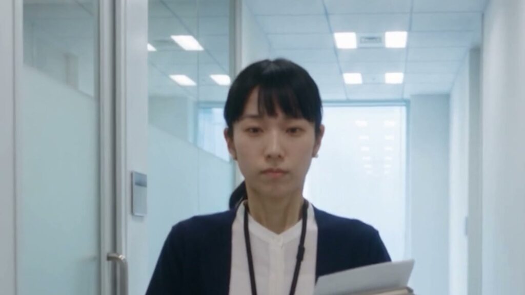 AIドラマ『派遣監査人』で、佐倉が書類を手に廊下を歩いていく場面